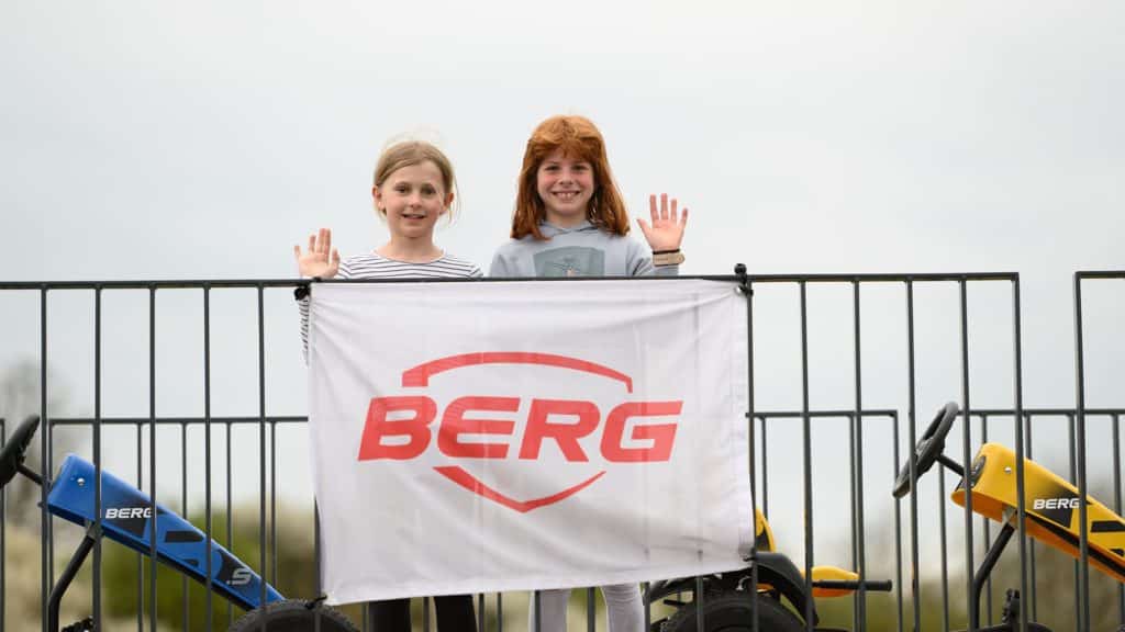 Zwei Mädchen stehen hinter einem Banner mit der Aufschrift BERG in roter Farbe