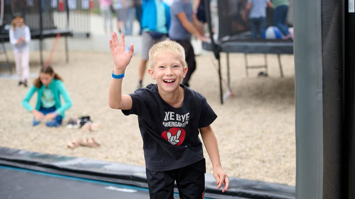 Kind freut sich und lacht auf einem Trampolin.