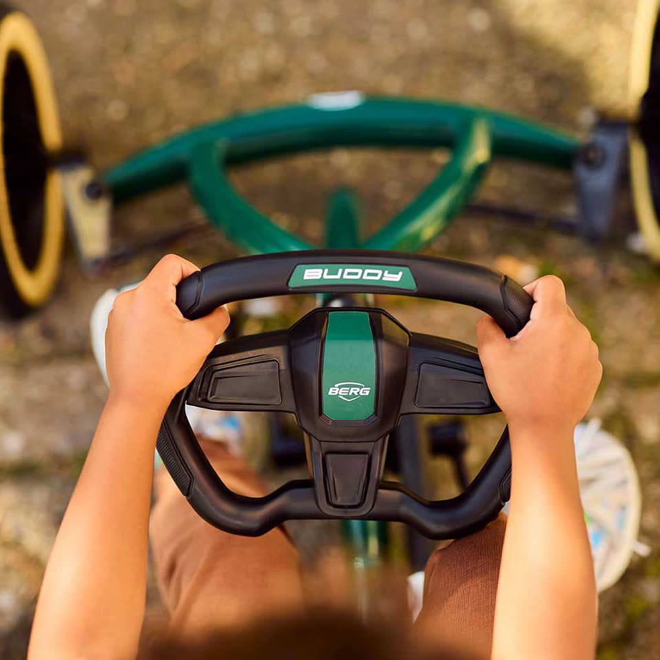 Kind hält das Lenkrad des Buddy Retro Green mit beiden Händen fest.