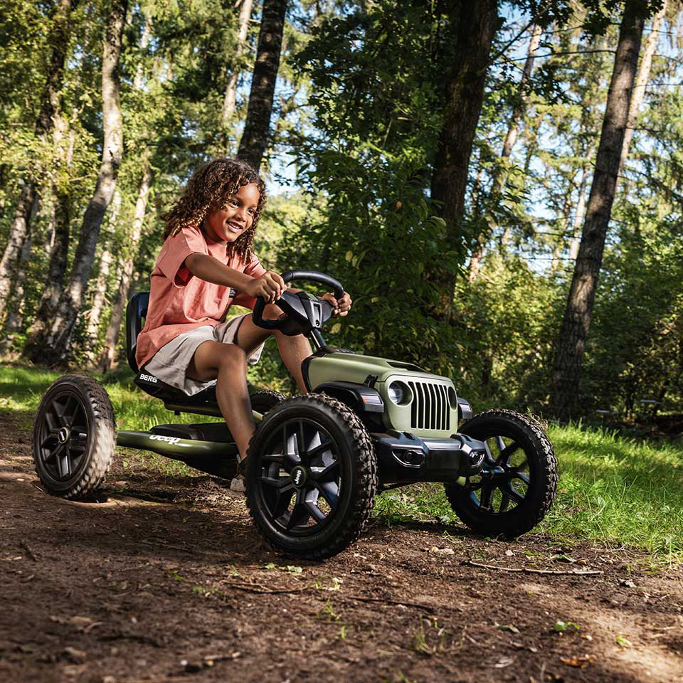 Mädchen fährt mit dem BERG Buddy Jeep Wrangler Pedal-Gokart outdoor durch den Wald